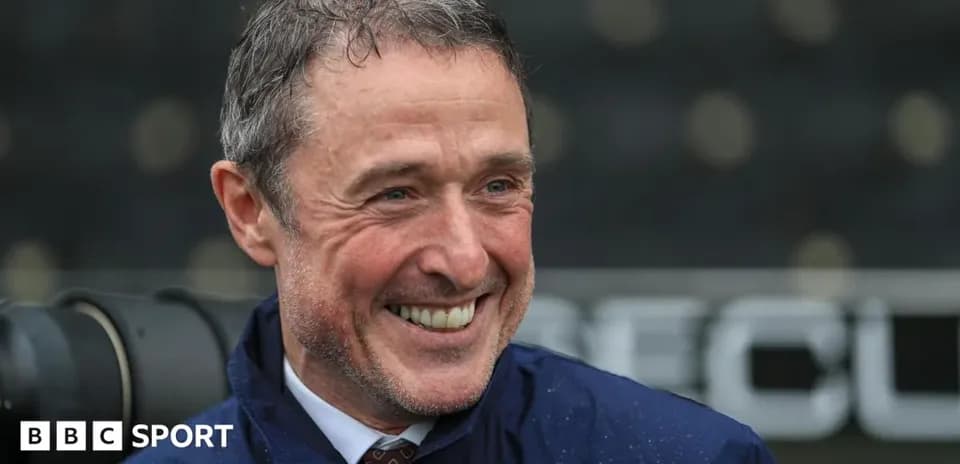 Man smiling in a raincoat at stadium