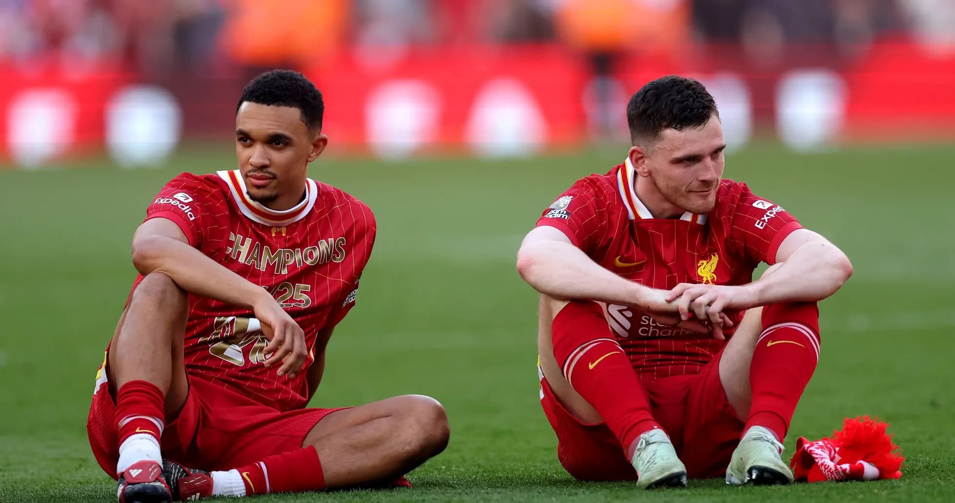Two Liverpool players sitting on the pitch post-match