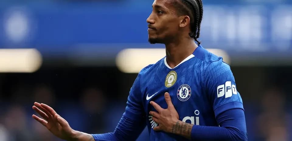 Player in blue Chelsea jersey gesturing to fans