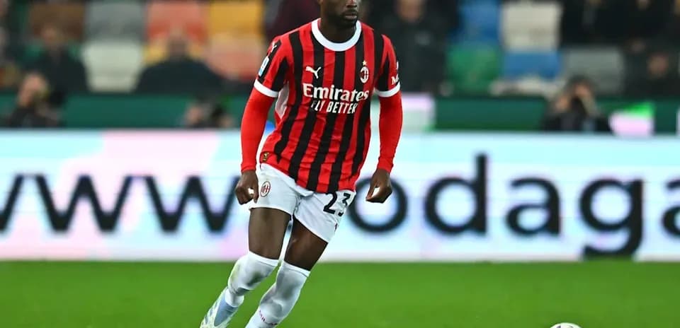 Player in AC Milan jersey dribbling the ball