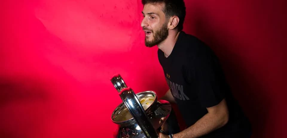 Player holding a trophy against red background