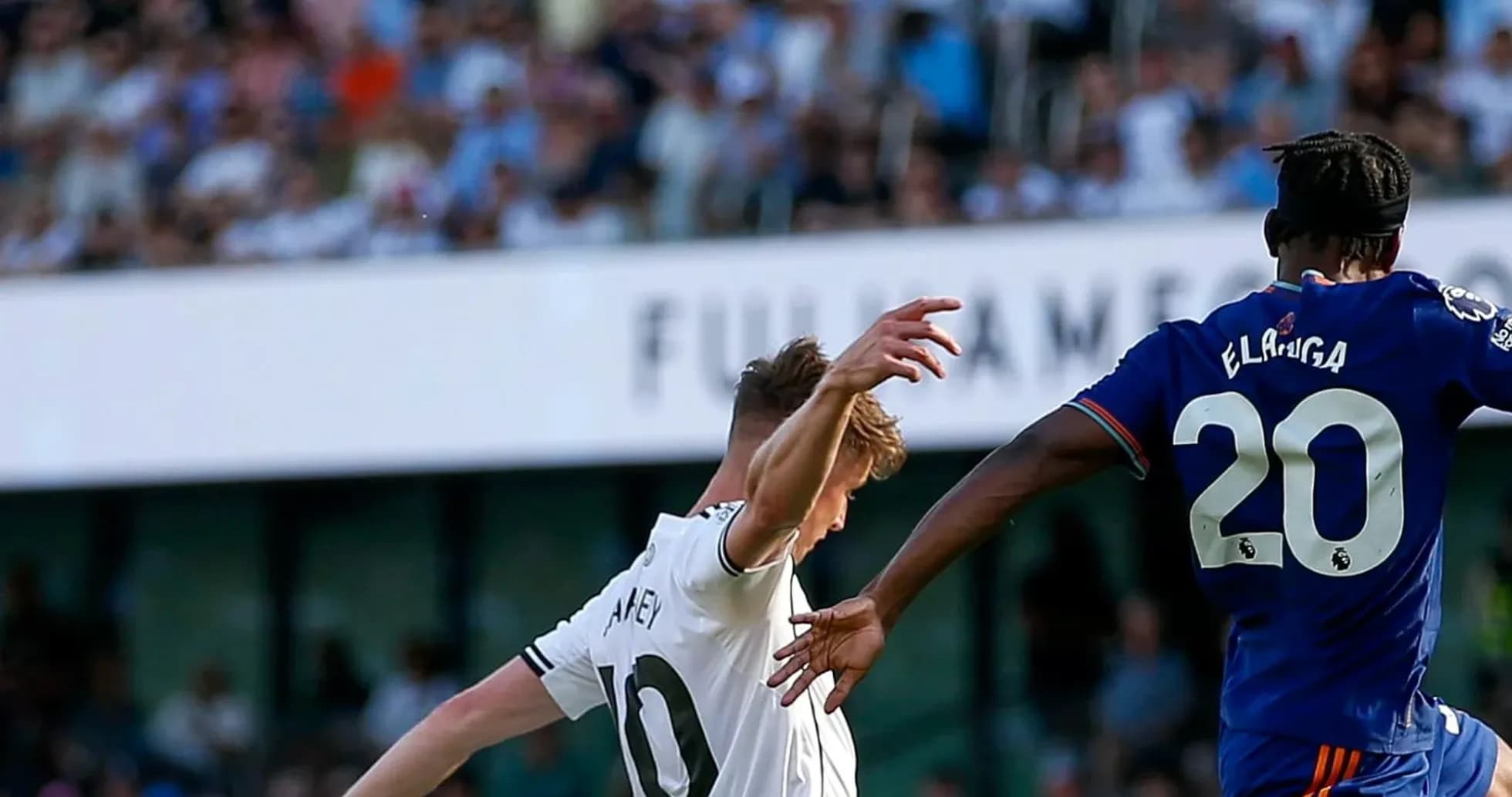 Fulham player challenging Newcastle opponent for the ball