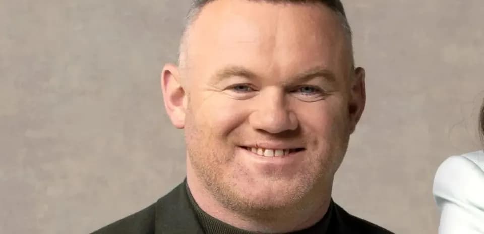Man smiling in a black jacket against neutral background
