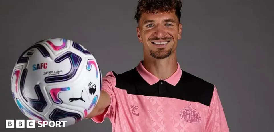 Player posing with football in pink kit