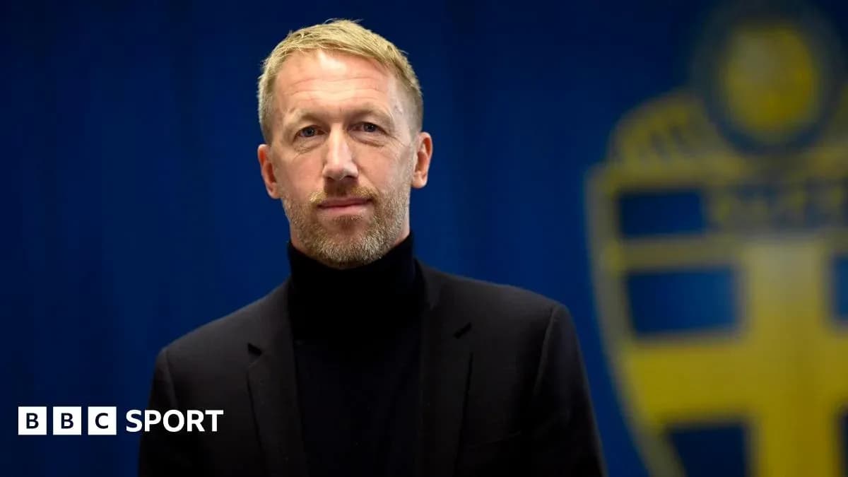 Man in black suit standing in front of blue backdrop