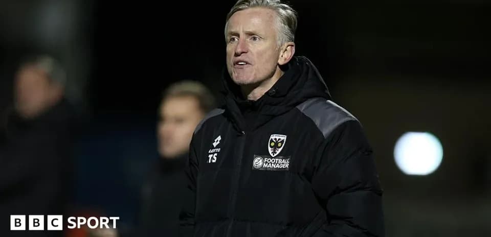 Manager in a jacket observing the match