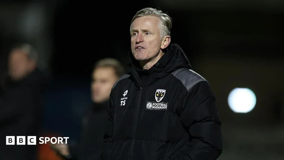 Manager in a jacket observing the match