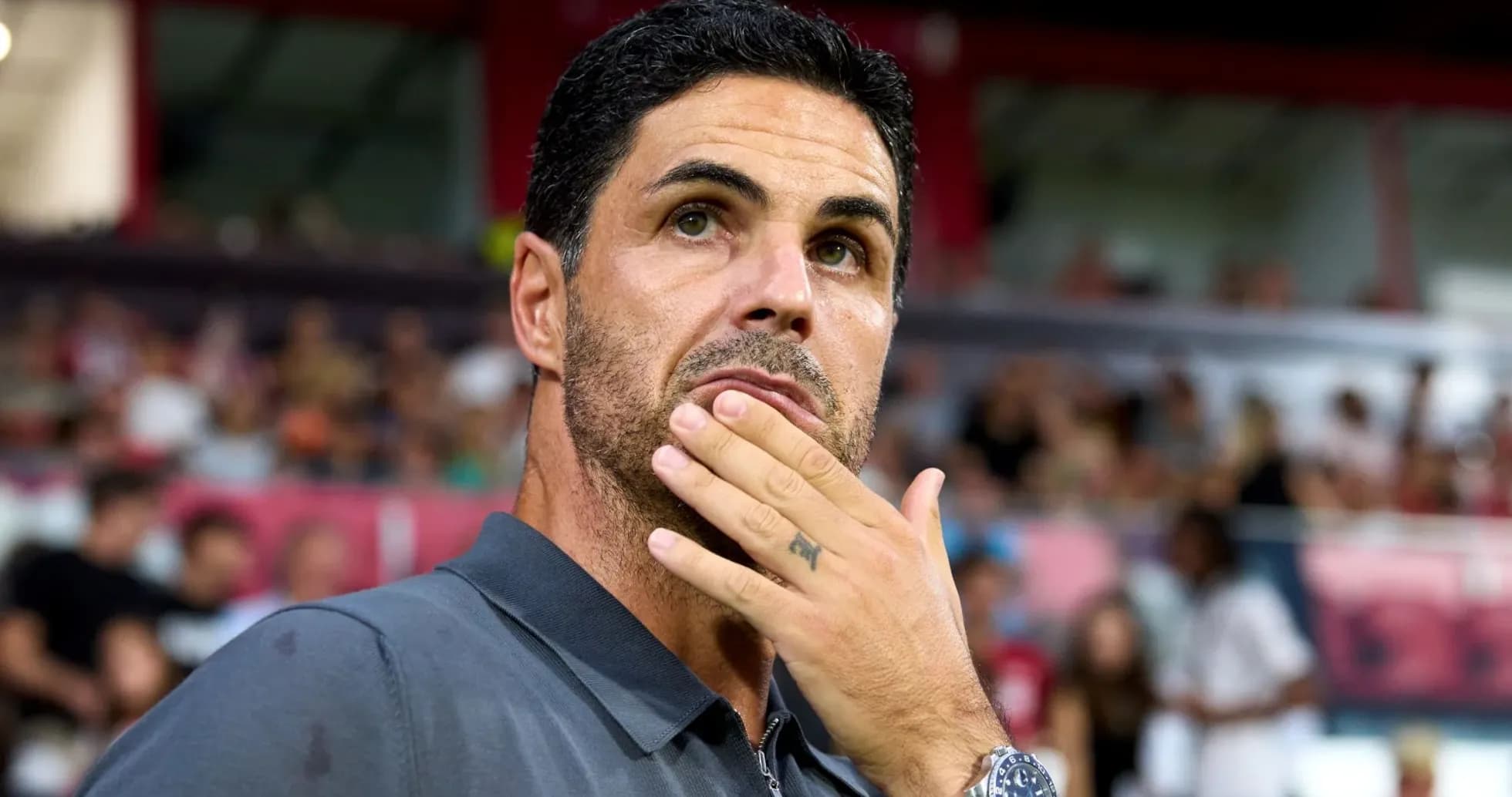 Coach pondering during a match with spectators in background
