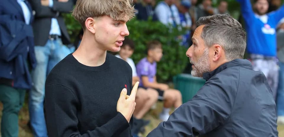 Two men engaged in a discussion near spectators