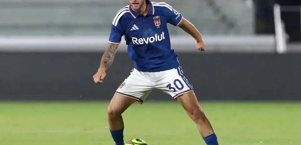 Player in blue kit dribbling a soccer ball
