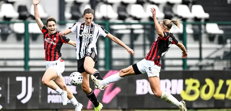 Juventus player dribbling past AC Milan defenders