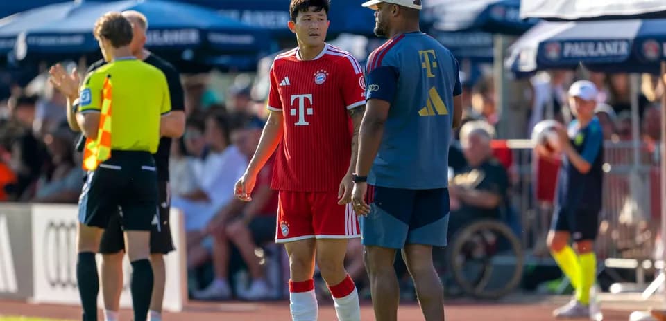 Bayern Munich player conversing with coach during match