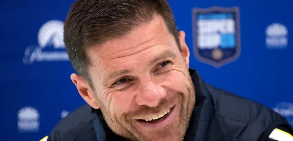 Coach smiling during press conference with blue backdrop