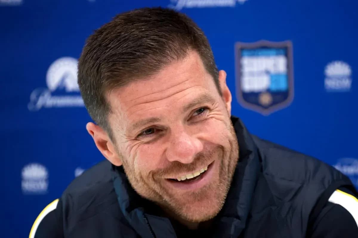 Coach smiling during press conference with blue backdrop