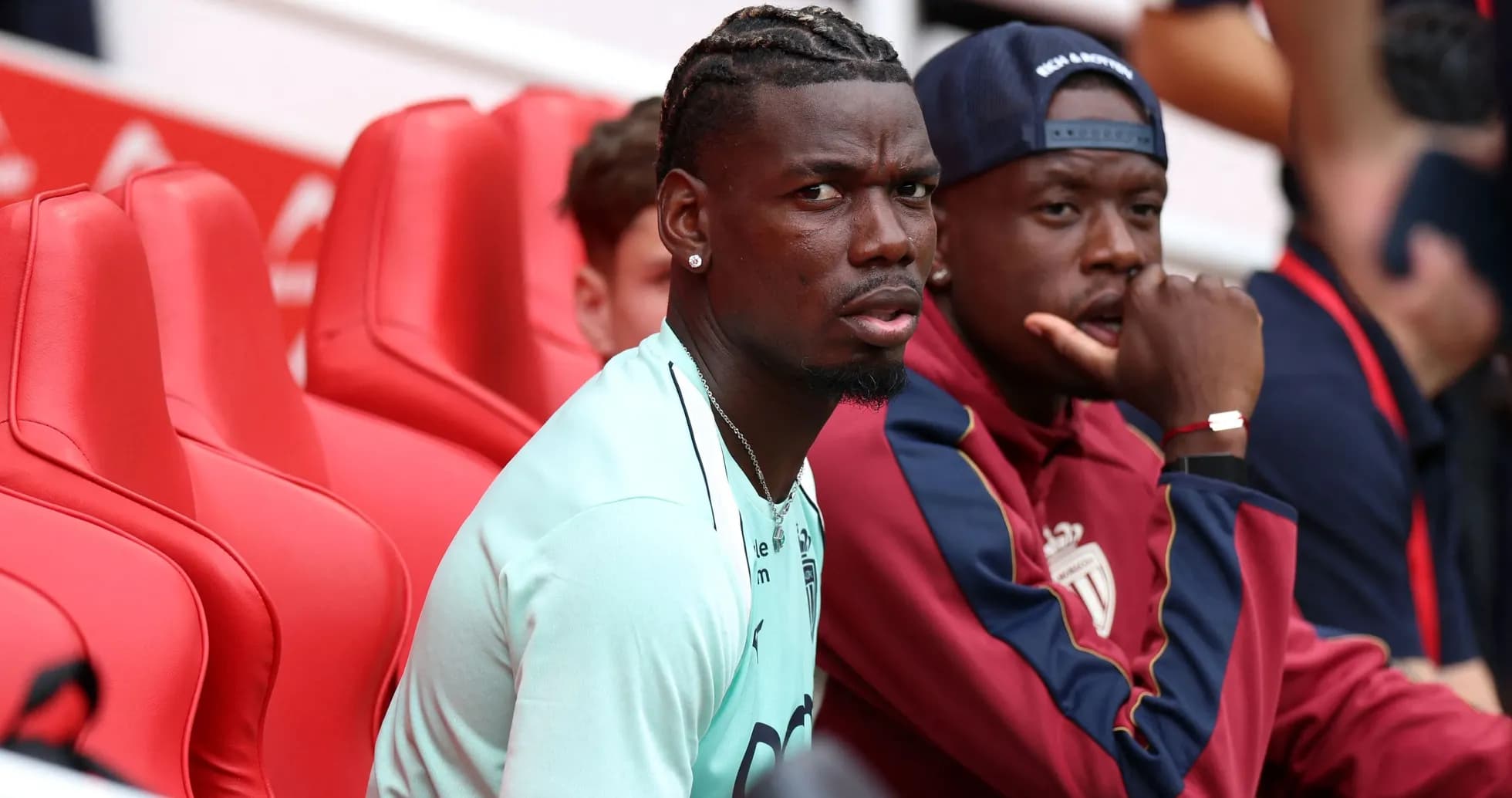 Two players seated on red bench during match