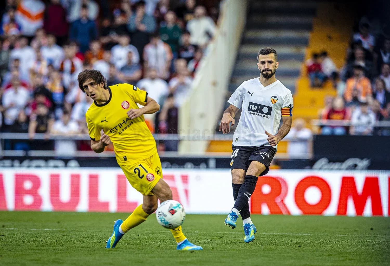Valencia player challenges Girona opponent for the ball