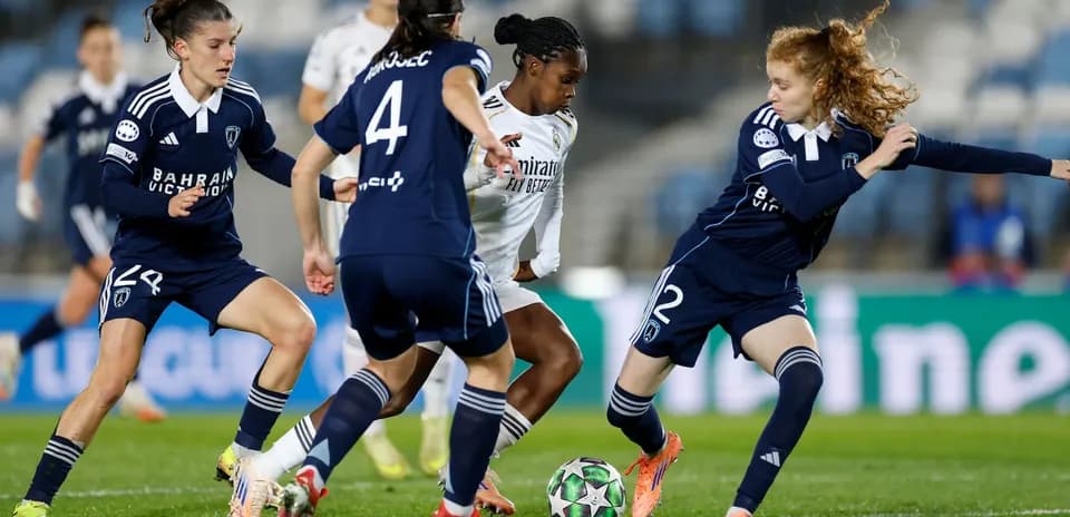Real Madrid W player dribbling past Paris FC W defenders