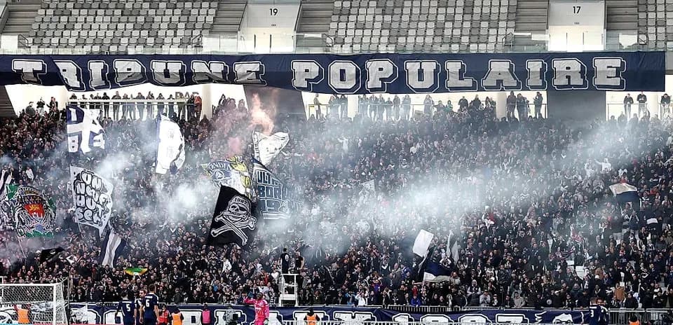 Crowd celebrating with flags and smoke in stadium