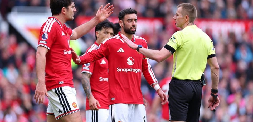 Manchester United players discussing with referee