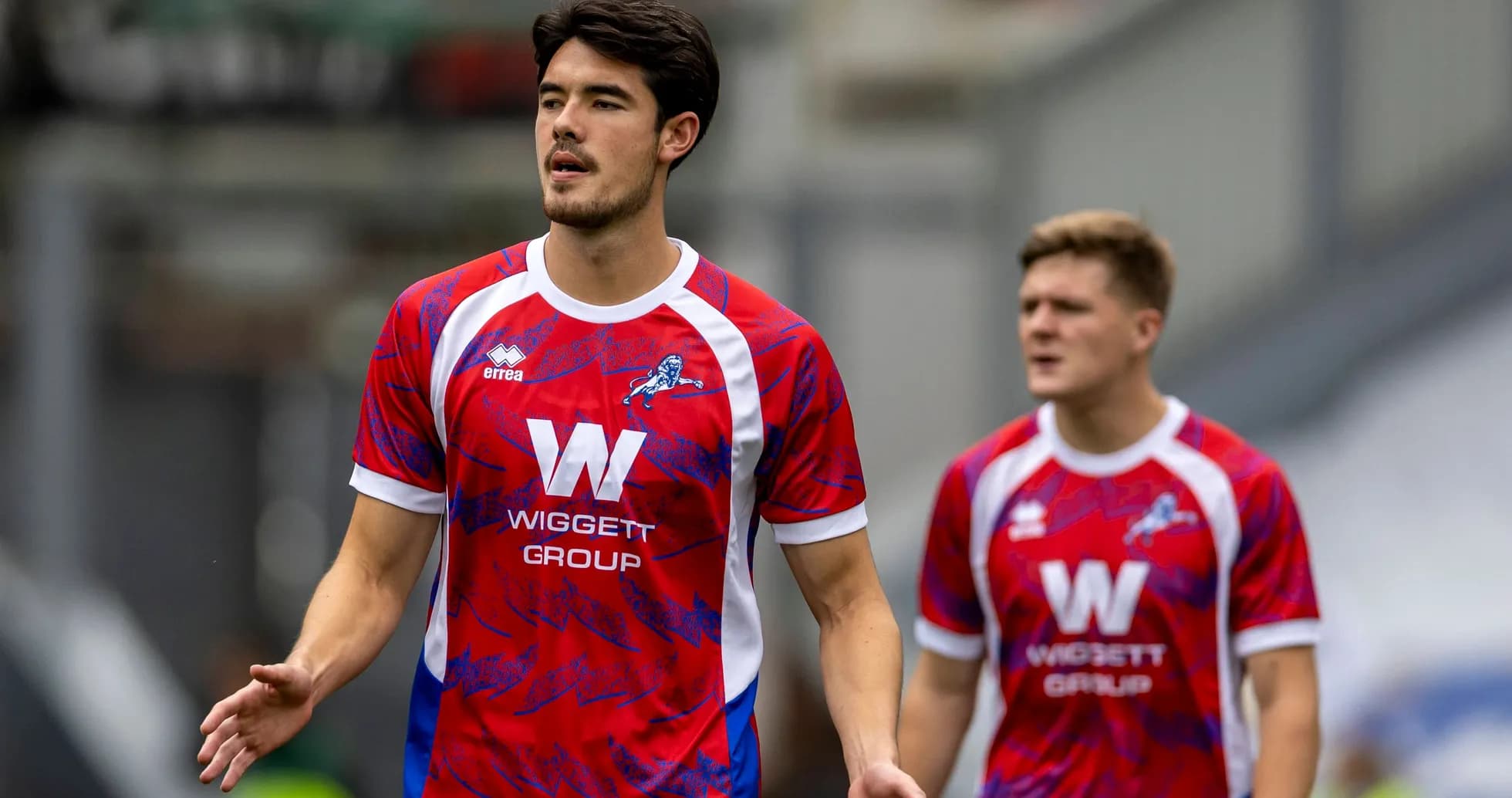 Two players in red and blue football kits on pitch