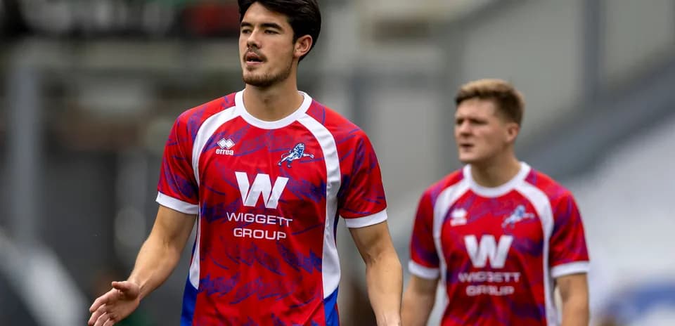 Two players in red and blue football kits on pitch