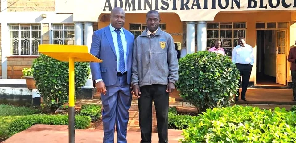 Two individuals posing in front of school building