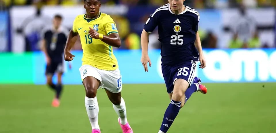 Player from Scotland dribbling past Brazilian opponent