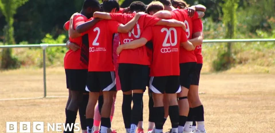 Team in red jerseys huddled together on field