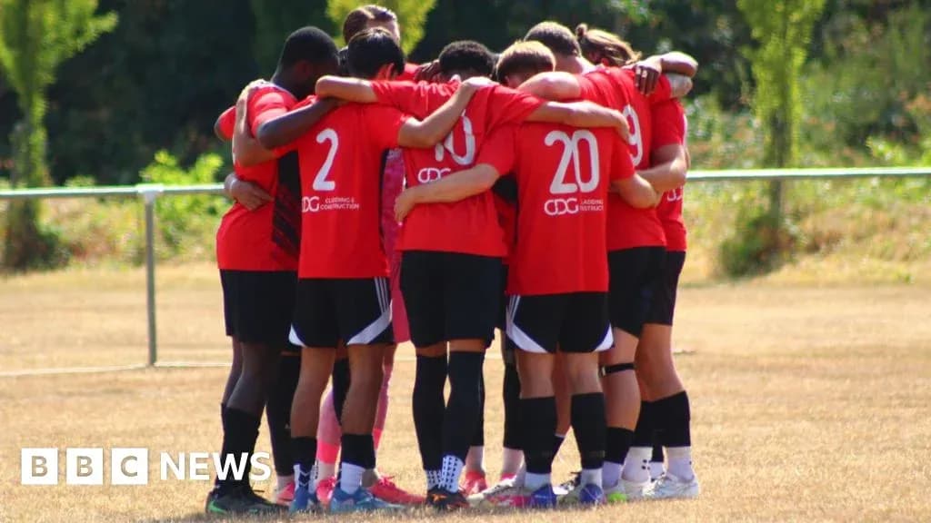 Team in red jerseys huddled together on field