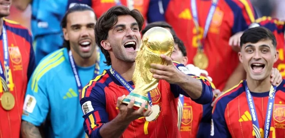 Player celebrating with FIFA World Cup trophy surrounded by teammates