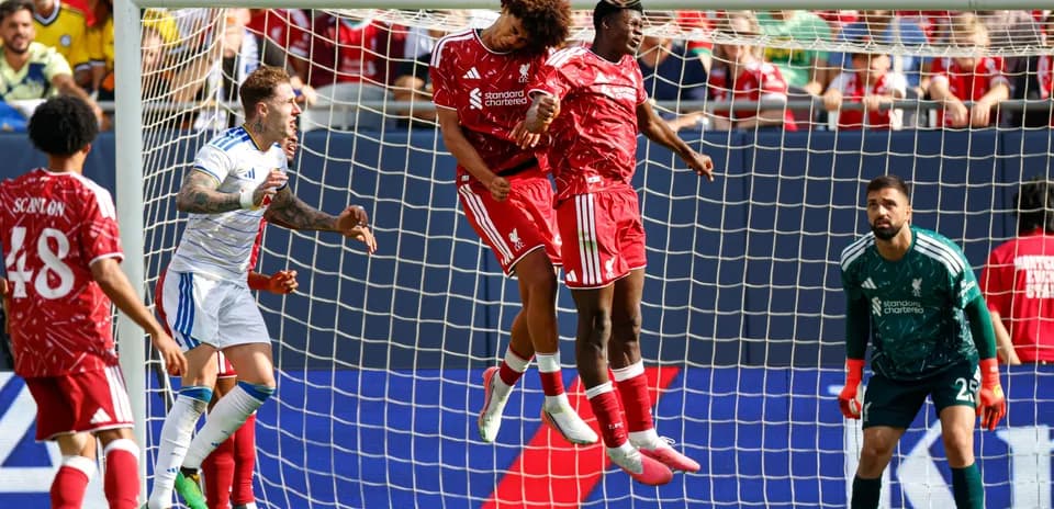 Two players jumping to head the ball in goal area