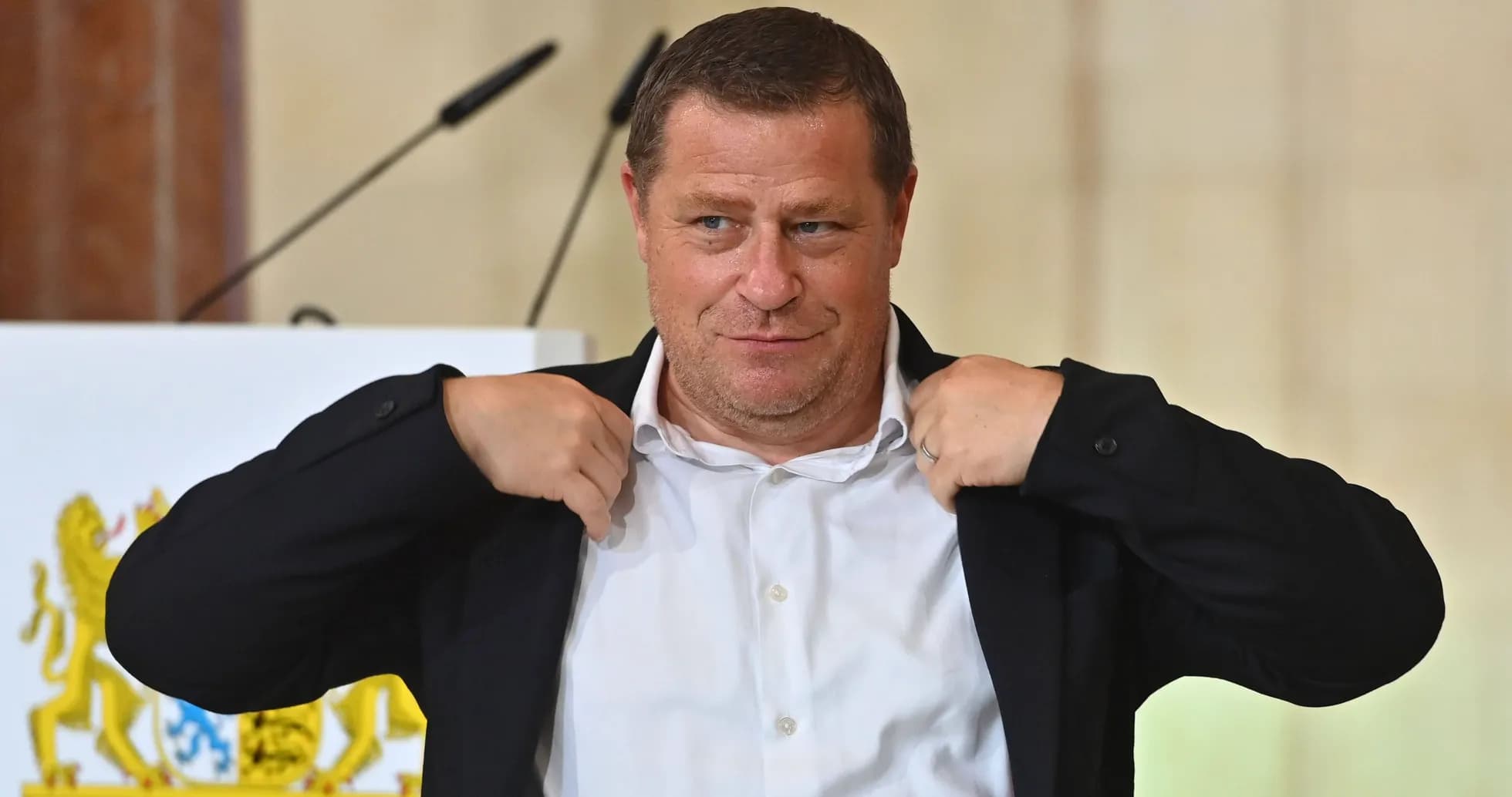 Man adjusting his jacket at a podium