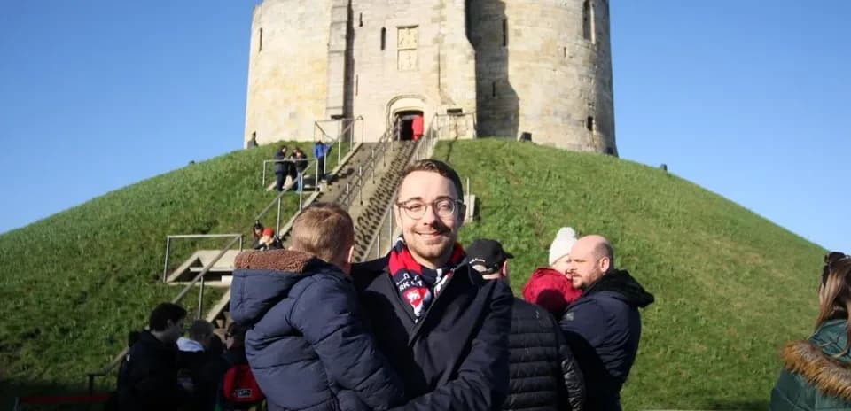 Person holding child in front of historic tower