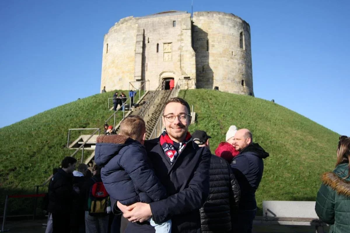 Person holding child in front of historic tower
