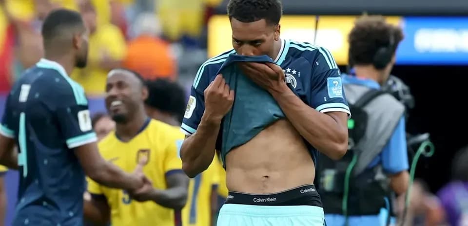 Player pulling up shirt after match, teammates in background