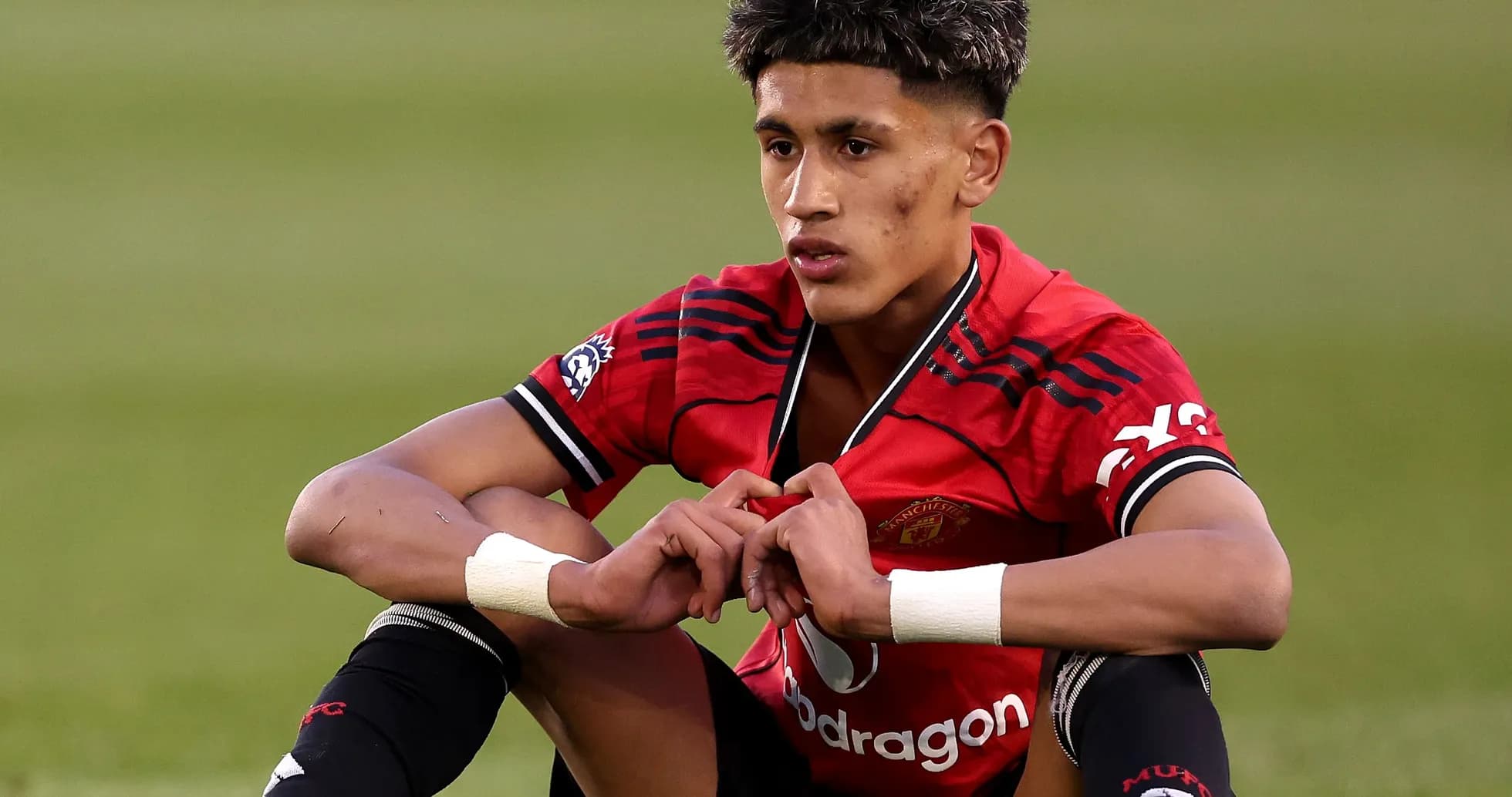 Player sitting on pitch in Manchester United jersey