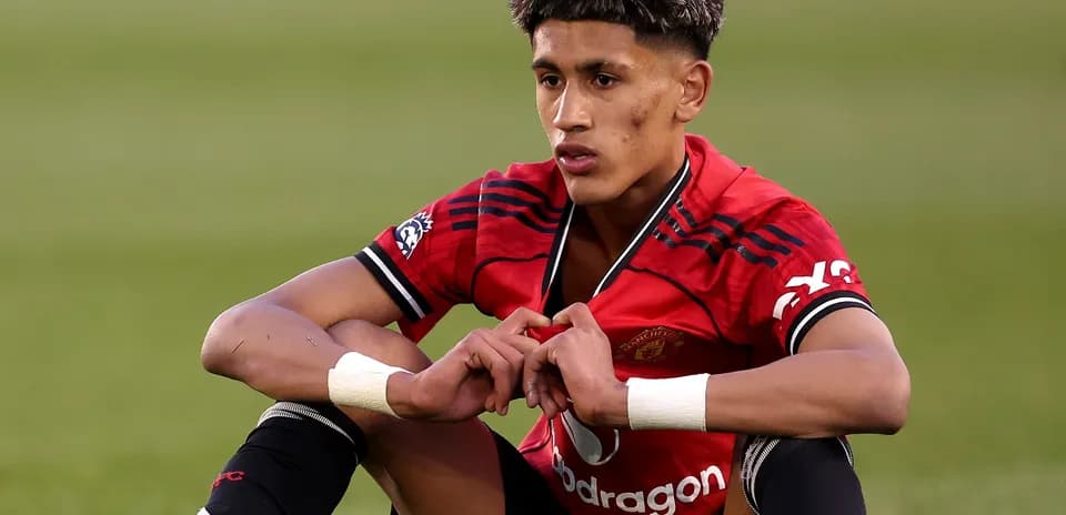 Player sitting on pitch in Manchester United jersey