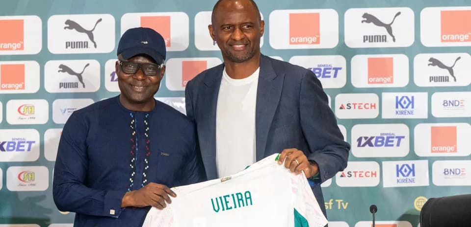 Two men holding a jersey at press conference