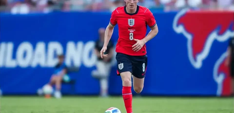 Player in red kit dribbling ball on field