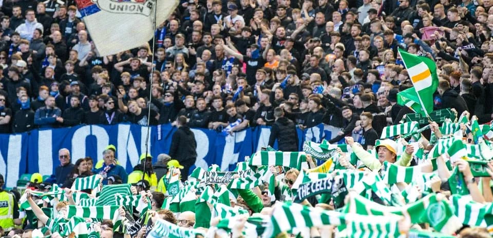 Celtic fans waving scarves in stadium crowd