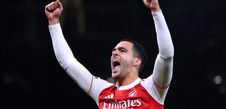 Player celebrating with raised arms in Arsenal jersey