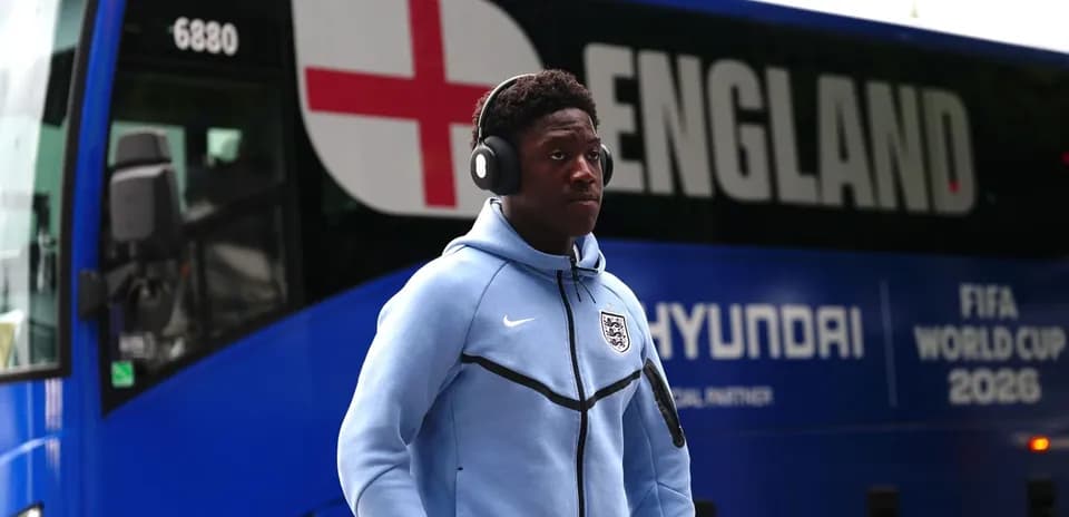 Player wearing headphones near England team bus