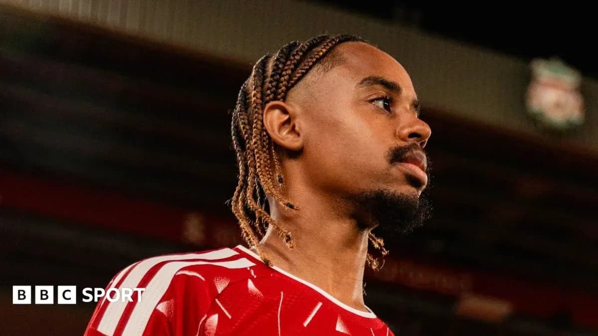 Player in red kit posing at stadium