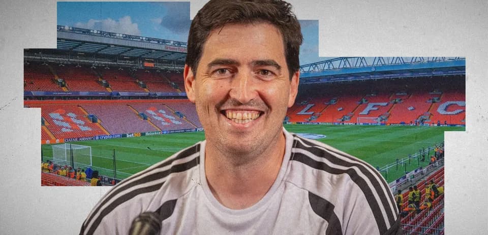 Coach smiling in front of Anfield stadium backdrop
