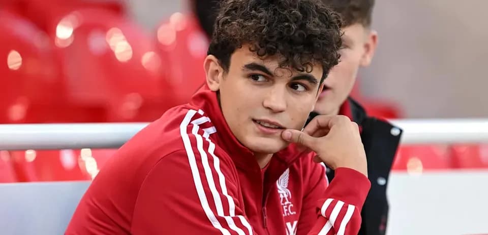Player in Liverpool FC tracksuit sitting on bench
