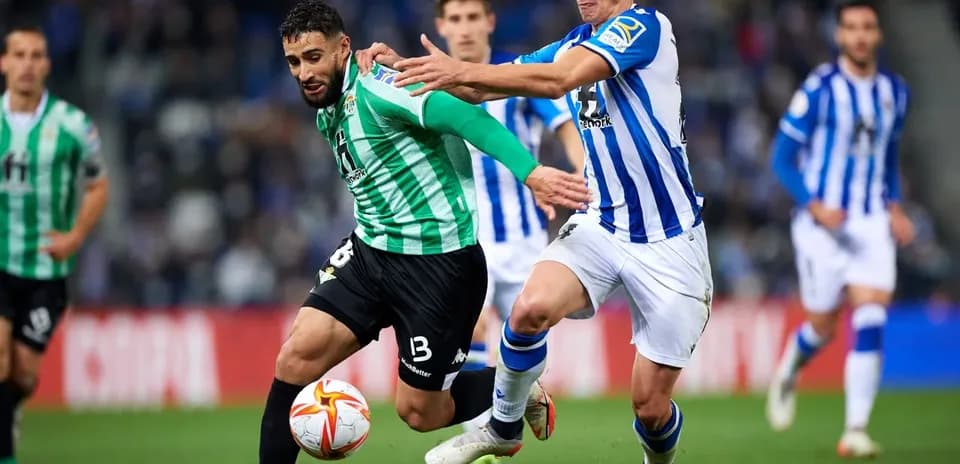 Real Betis player challenged by Real Sociedad opponent