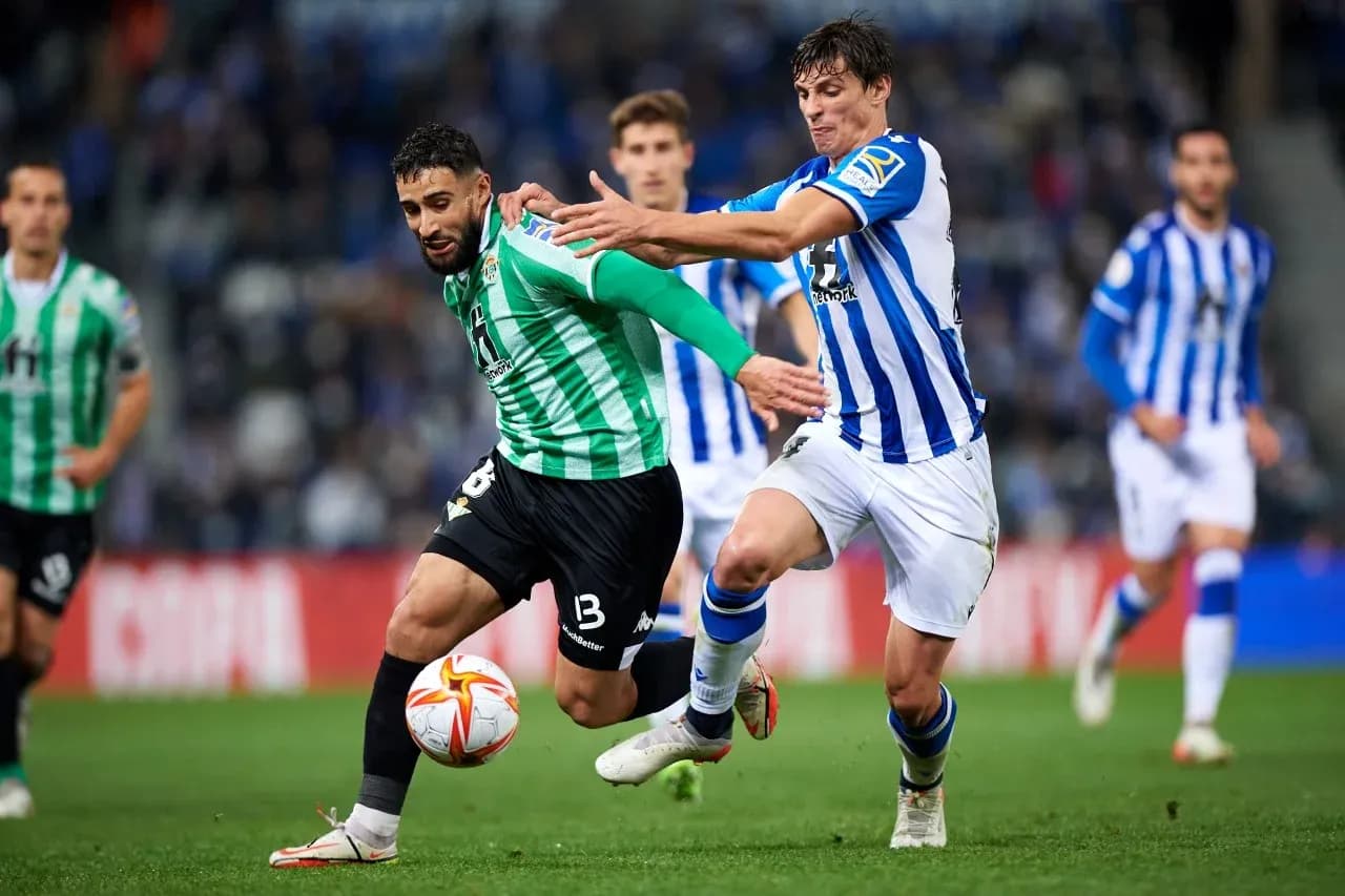 Real Betis player challenged by Real Sociedad opponent