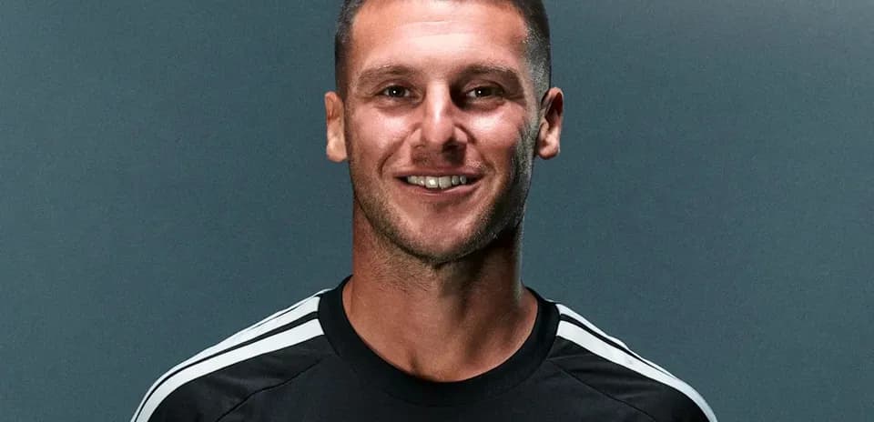 Player posing in black jersey with club logo