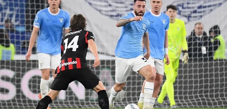 Lazio player dribbling against AC Milan opponent