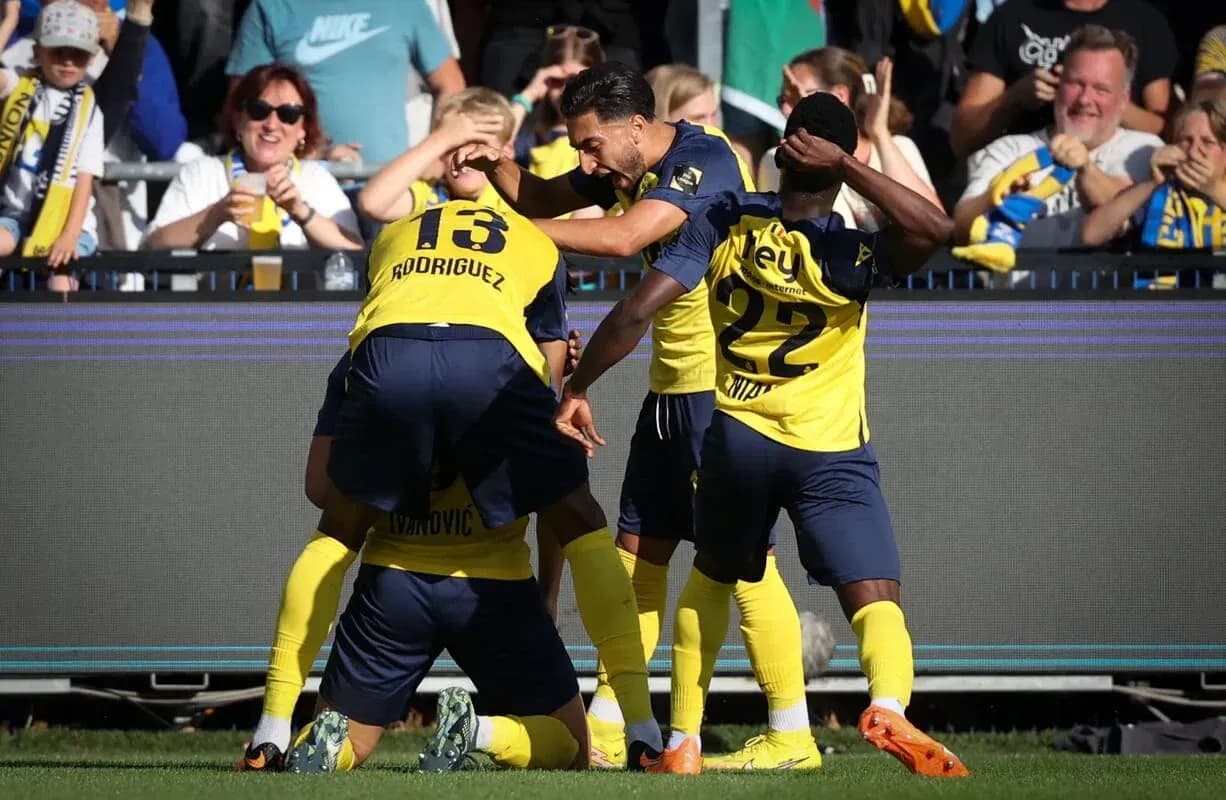 Players celebrating a goal with fans in background